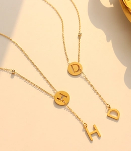 Detail of 18k gold plated Y-shaped tassel necklace with MHD hollow letters and zircon