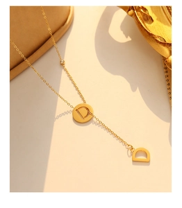 Macro detail of 18k gold plated Y-shape fringe necklace with zircon and D letter charms