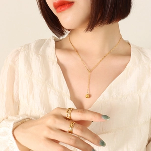 Gold-plated geometric ball pendant necklace and ring set worn by a female model