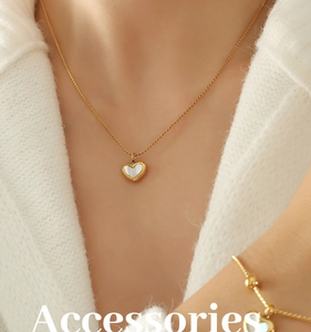 Close-up of heart-shaped white shell pendant and golden necklace on knit fabric