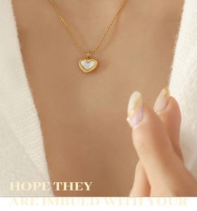 Close-up of heart-shaped gold necklace with white mother of pearl inlay on model