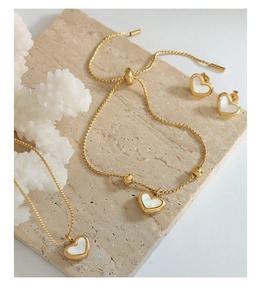 Close-up of gold heart jewelry set with white shell inlay on stone and coral decor