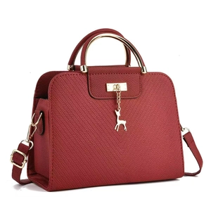 Deep red embossed crossbody bag with golden deer charm and curved metal handle