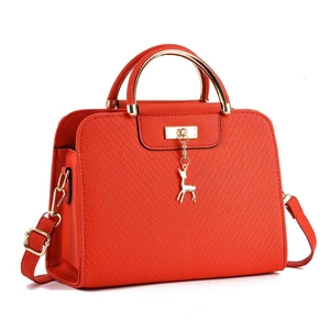 Detail of orange crosshatch leather tote with gold deer charm and metal handles