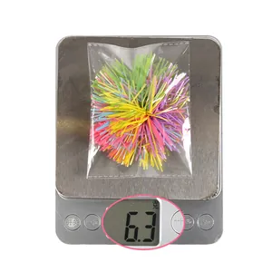 Close-up of colorful sparkling tinsel pom-poms for Easter hair clips on a digital scale