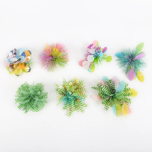 Detail of seven assorted colorful pom-poms featuring glitter, fringe and green striped textures