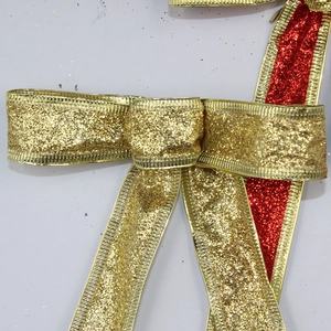Close-up of glittery red and gold Christmas ribbon bow with detailed metallic trim edging