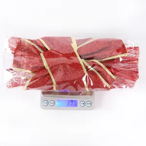 Détail d'un grand nœud de Noël rouge à bords dorés pesant 39,5 g sur une balance