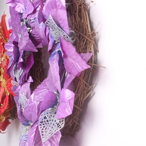 Détail d'une couronne de Noël DIY avec fleurs violettes et feuilles argentées pailletées
