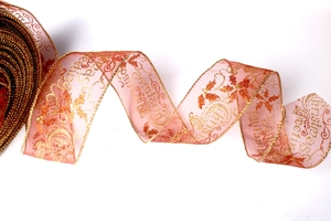 Macro shot of red sheer Christmas ribbon featuring golden greetings and leaf patterns