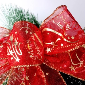 Red sheer Christmas bow with gold Merry Christmas print on festive green pine branches