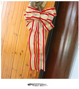 Detail of red and gold striped Christmas bow hanging on a wooden door with metal ring