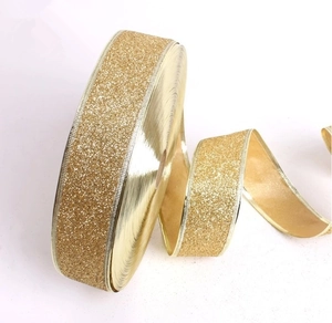 Close-up of golden glitter Christmas ribbon roll with sparkling texture and metallic edges