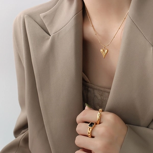 Ensemble collier pendentif coeur plaqué or 18K et bagues porté par un mannequin