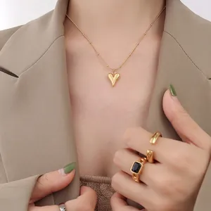 Ensemble collier pendentif cœur doré et bagues vintage porté par un mannequin