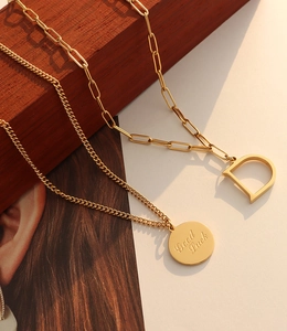 Detalle de collar de doble capa chapado en oro 18K con moneda Good Luck y colgante letra D