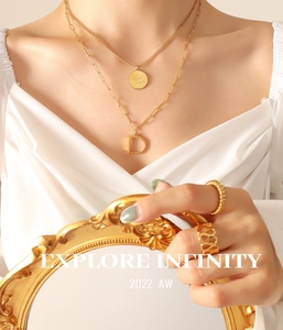 Detalle de collar doble capa bañado en oro 18K con moneda Good Luck y colgante letra D