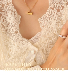Close-up of a gold necklace with geometric pendant and a matching baguette stone ring