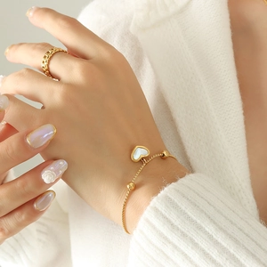 Elegant gold heart bracelet with white shell inlay and matching chain link ring on model