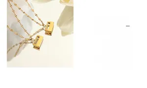 Detail shot of the golden rectangular cutout padlock pendant and fine chain texture