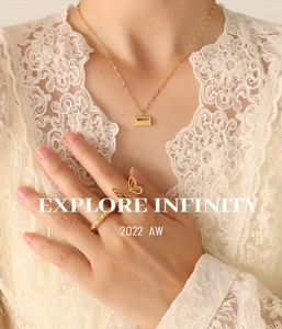 Detail of 18K gold butterfly ring and minimalist pendant necklace on model