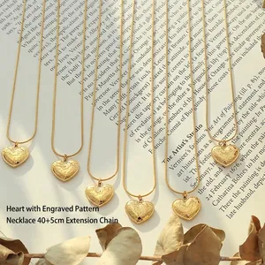 Golden heart pendant necklace with 'I love you' engraving on snake chain on vintage book