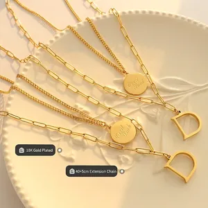 Collar de capas en oro de 18K con colgantes Good Luck y letra D sobre cerámica blanca