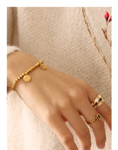 Detail eines vergoldeten Perlenarmbands mit Fu-Anhängern und karierten Ringen