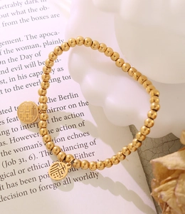 Makroaufnahme Goldperlenarmband mit hohlen Fu- und Xi-Glücksbringern im Detail