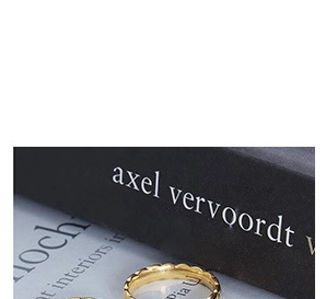 Macro shot of a wave-textured gold ring with glossy finish on a black design book