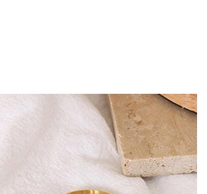 Detailed view of a wide polished gold ring on textured stone and knit fabric background