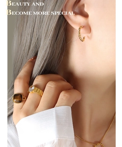 Vue détaillée des boucles d'oreilles torsadées dorées et des bagues serties de pierres
