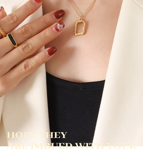 Close-up of minimalist gold geometric rectangular pendant necklace on a model