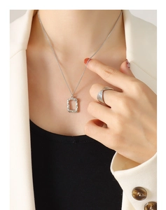 Detailed view of silver liquid metal rectangular pendant and layered ring on a model