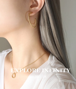 Gros plan sur un ensemble collier et boucles d'oreilles dorés à texture corde torsadée