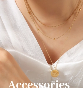 Detailed close-up of a triple-layered gold necklace with a Good Luck engraved round pendant