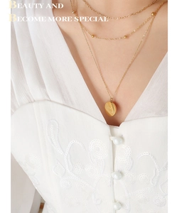 Close-up of triple-layered gold coin necklace with Good Luck engraving on female model