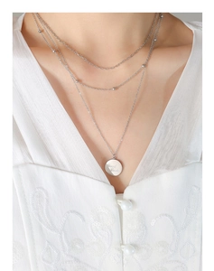 Close-up of triple-layered silver necklace with round Good Luck coin pendant on model