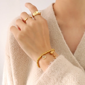 Goldenes Perlenarmband mit Fu-Anhänger und Kürbis sowie elegante goldene Ringe