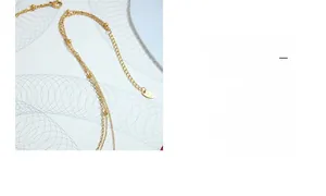 Detail of layered gold beaded necklace with an adjustable extender chain and logo tag