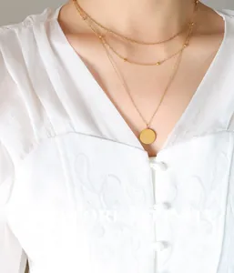 Detailed view of layered gold necklace with circular Good Luck coin pendant and beads