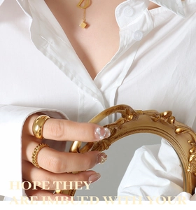 Close-up of golden letter D pendant necklace and textured rings with vintage frame