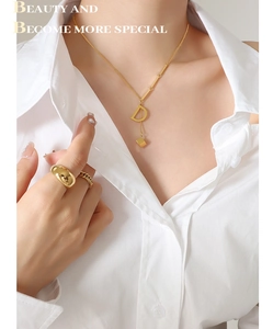 Detail of 18K gold-plated D-letter pendant necklace and rings on a model