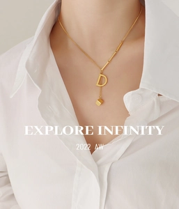 Detail of 18K gold plated D-letter pendant and golden cube on a delicate chain