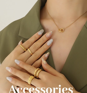 Detail shot of intertwined gold rings and double loop necklace on a model wearing green