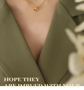 Detail of interlocking double rings pendant on a gold chain worn over a green blazer