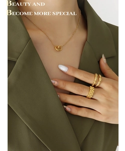 Detail of gold-plated interlocking ring necklace and textured rings on a model