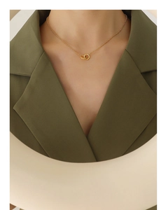 Close-up of interlocking double ring pendant on gold-plated titanium chain worn by a model