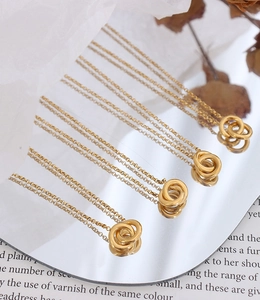 Detailed view of four interlocking double ring necklaces on a creative mirror surface