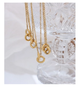 Detailed macro view of gold-plated interlocking double ring pendant necklace on glass